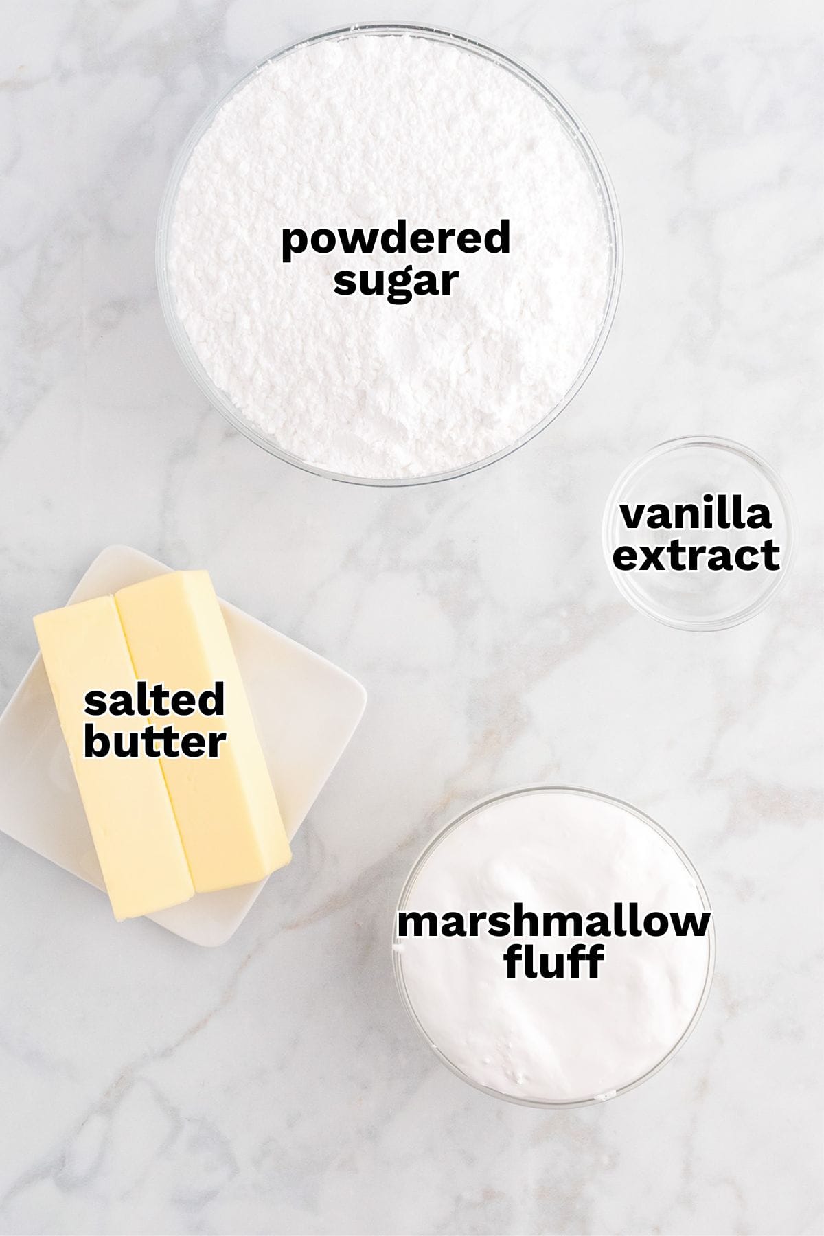 Bowls and plates containing powdered sugar, vanilla extract, salted butter, and marshmallow fluff are arranged on a white surface—perfect ingredients for an Easy Marshmallow Frosting.