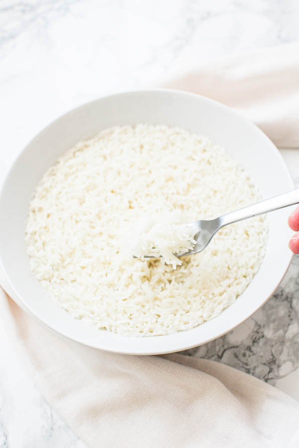 Basmati rice cooked in microwave in a white bowl. Ready to be served as a side dish with dinner.