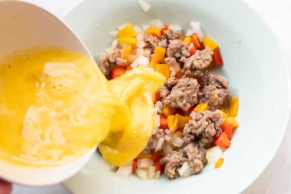 Egg mixture pouring over cooked sausage