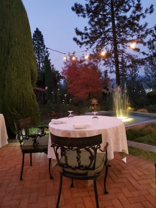 Romantic table for two under lights with a lighted fountain near it