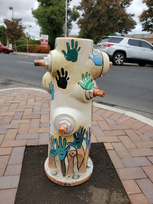 fire hydrant painted with hands all over it 