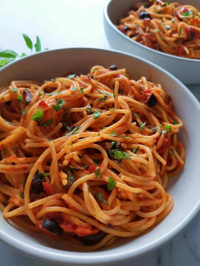 white bowl of spaghetti with red sauce