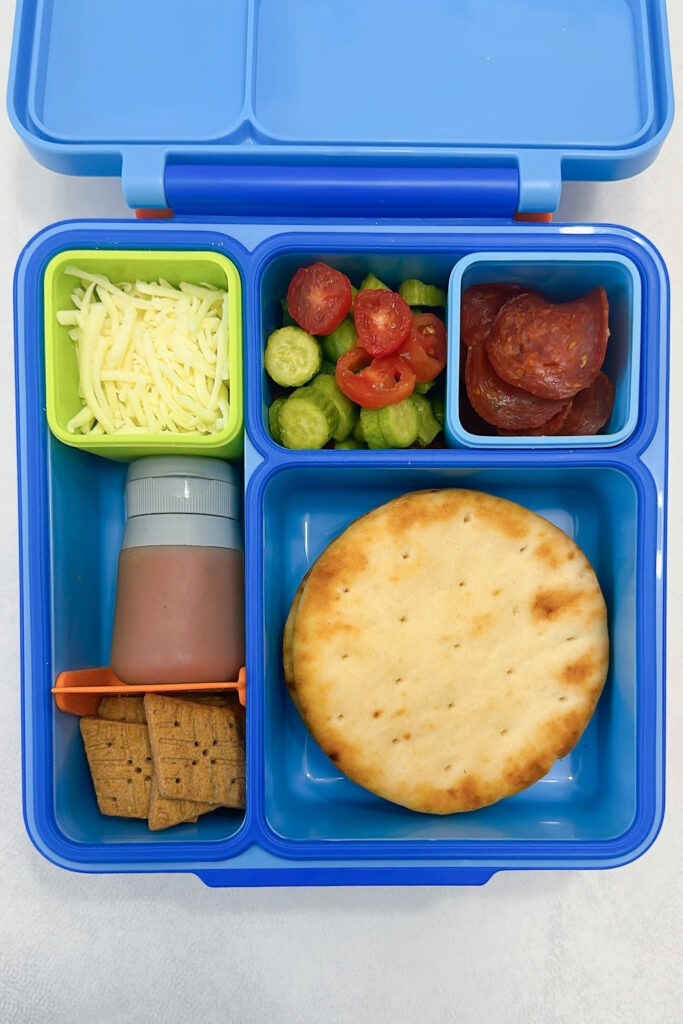 Naan rounds served with pizza sauce, mozzarella cheese, cucumbers, grapes, pepperoni, and graham crackers.