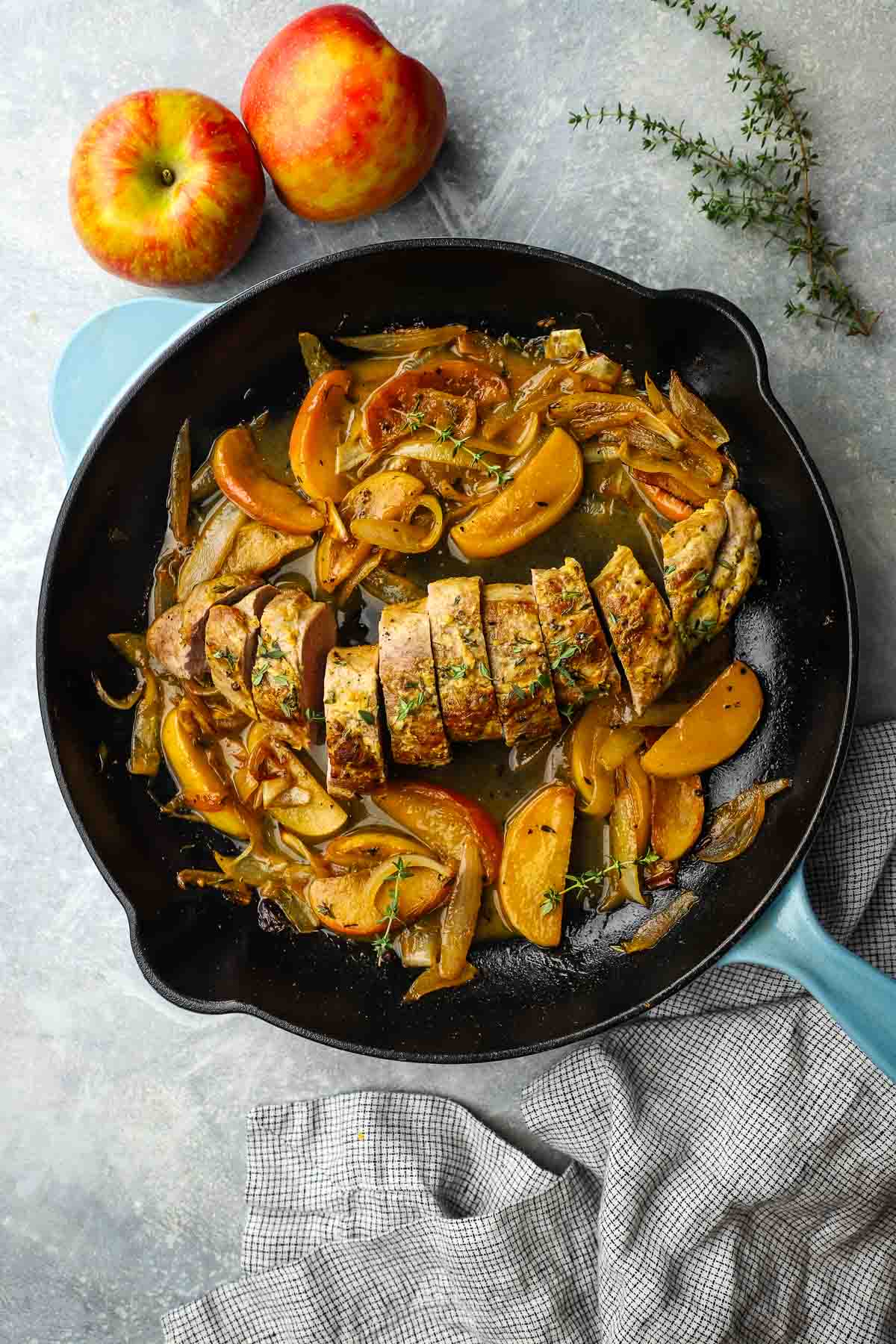 a skillet of pork tenderloin with apples and onions.