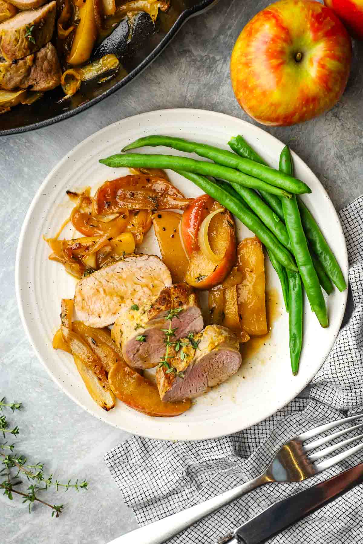 a plate served with pork tenderloin with apples and onions.