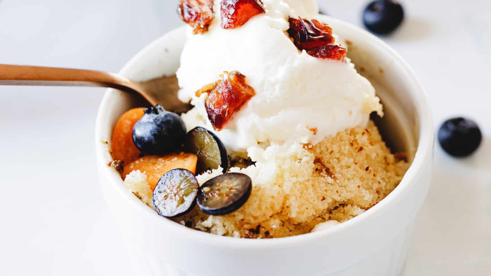 A bowl of ice cream and oranges on a blue tablecloth.