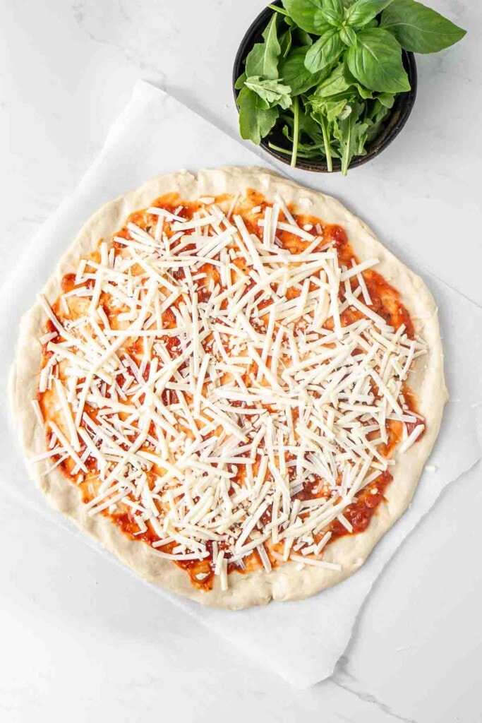 Making the pizza with sauce and cheese.