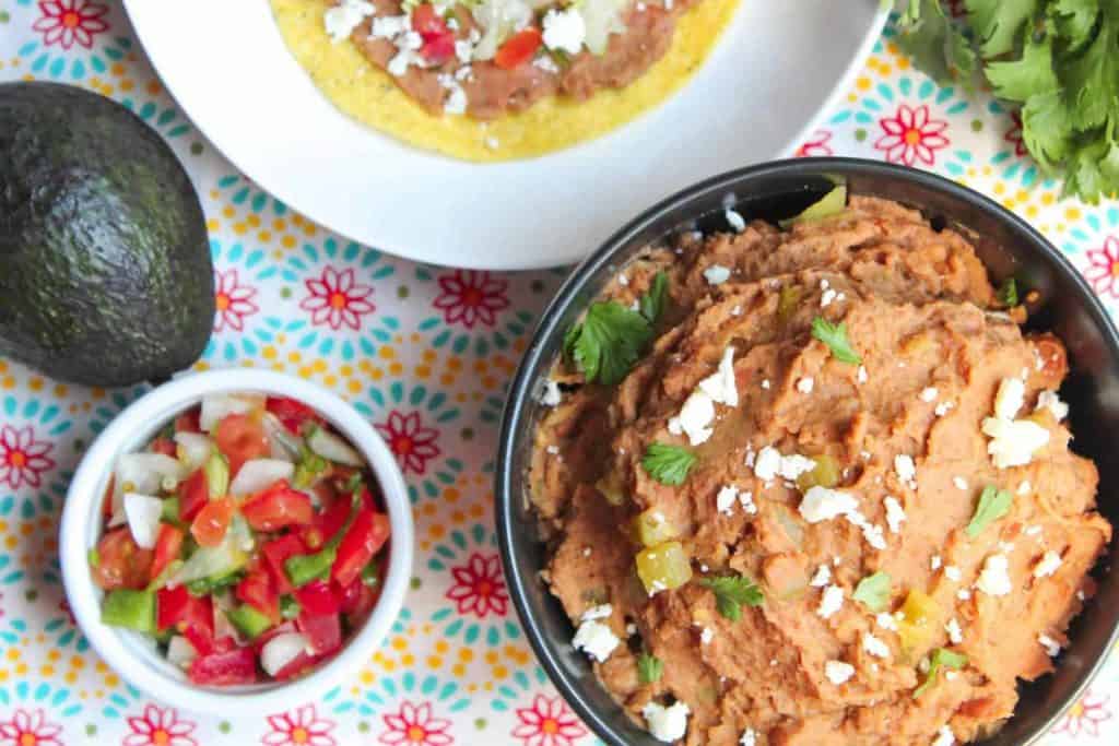 bowl of refried beans next to pico de Gallo