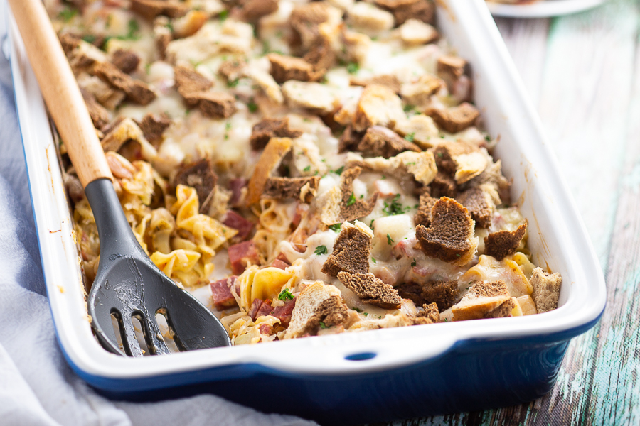 Reuben casserole in ceramic casserole dish on a green rustic wood background