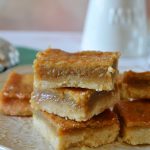 sugar pie squares stacked on a white plate and a green towel
