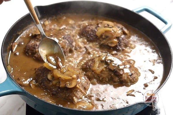 Pouring gravy over the top of the beef patties