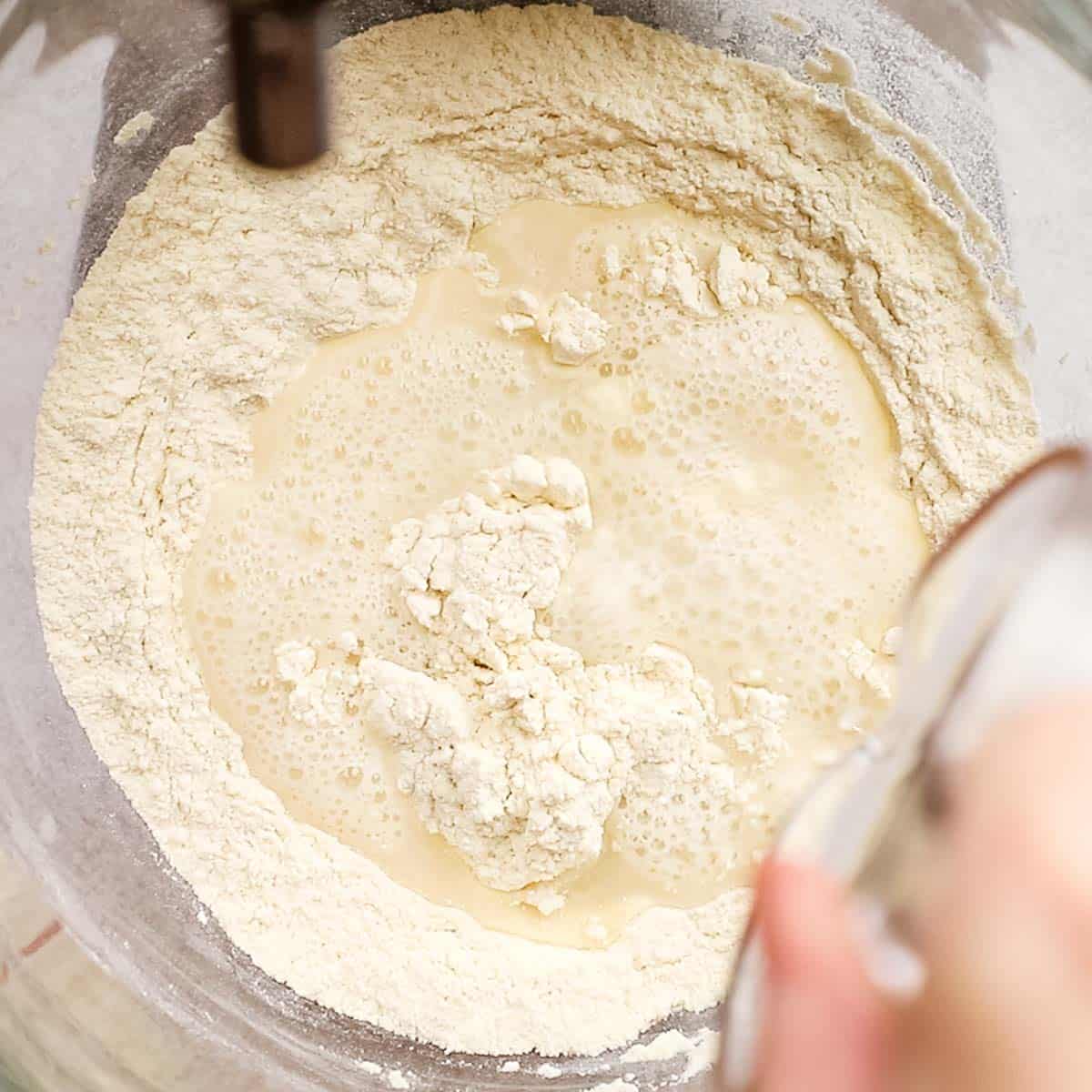 Water being added to dry ingredients to make pizza dough.