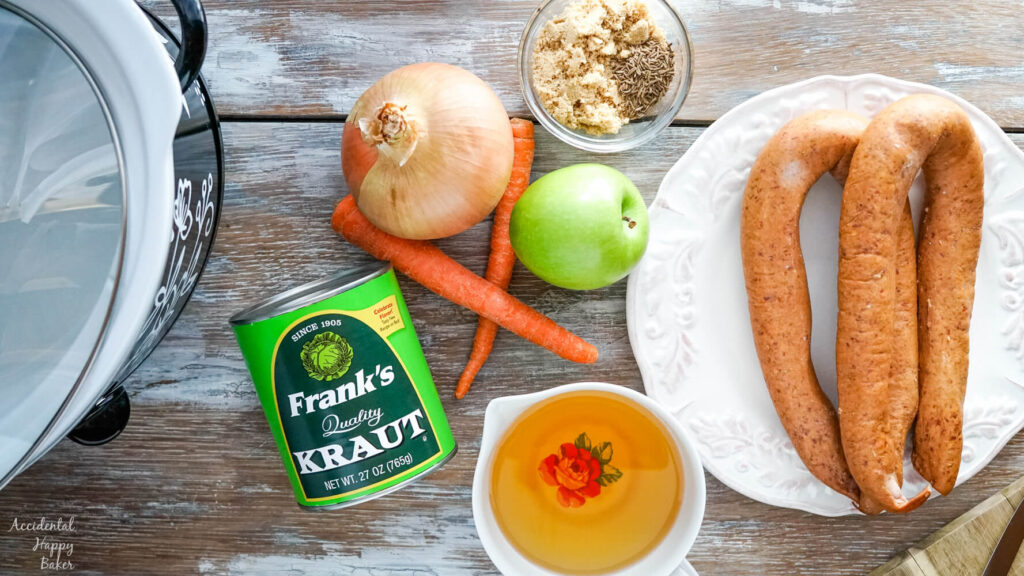 The ingredients needed for this recipe; sauerkraut, kielbasa, carrots, apple, onion, brown sugar, caraway seeds and apple juice. 