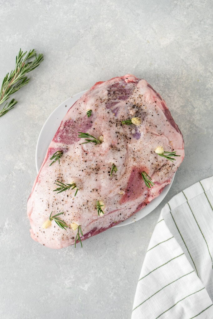 Preparing the lamb shoulder with garlic and rosemary.