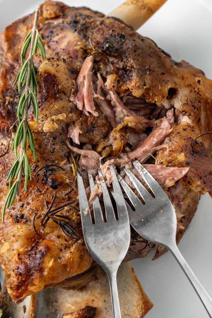 Pulling the lamb apart with two forks.