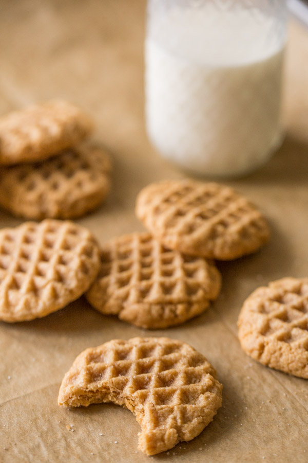 Small Batch Peanut Butter Cookies with a bite taken out of one of the cookies and a glass of milk in the background. 