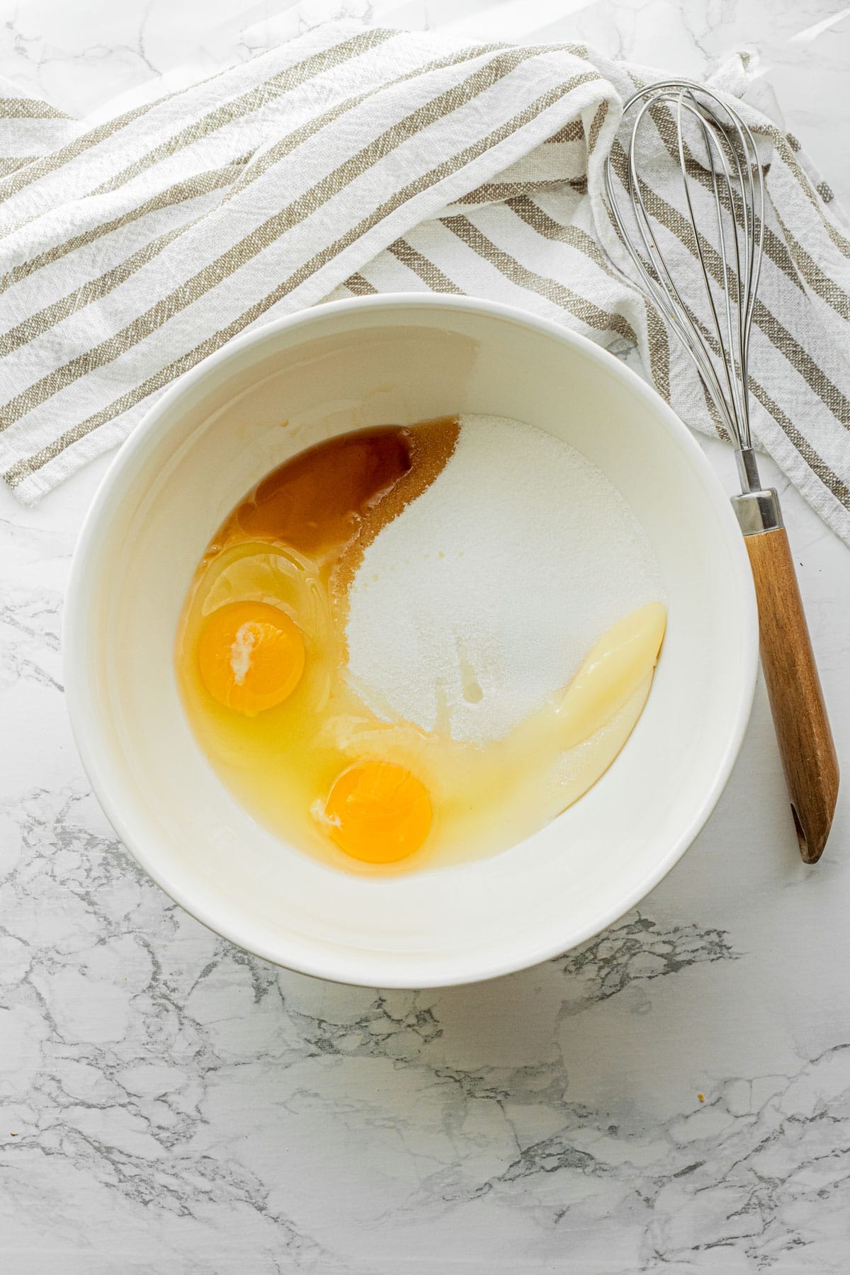 Eggs, sugar, vanilla, and sourdough discard in white bowl.