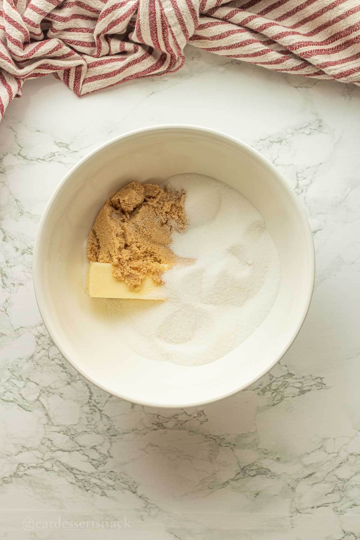 Butter and sugar in bowl on marble countertop.
