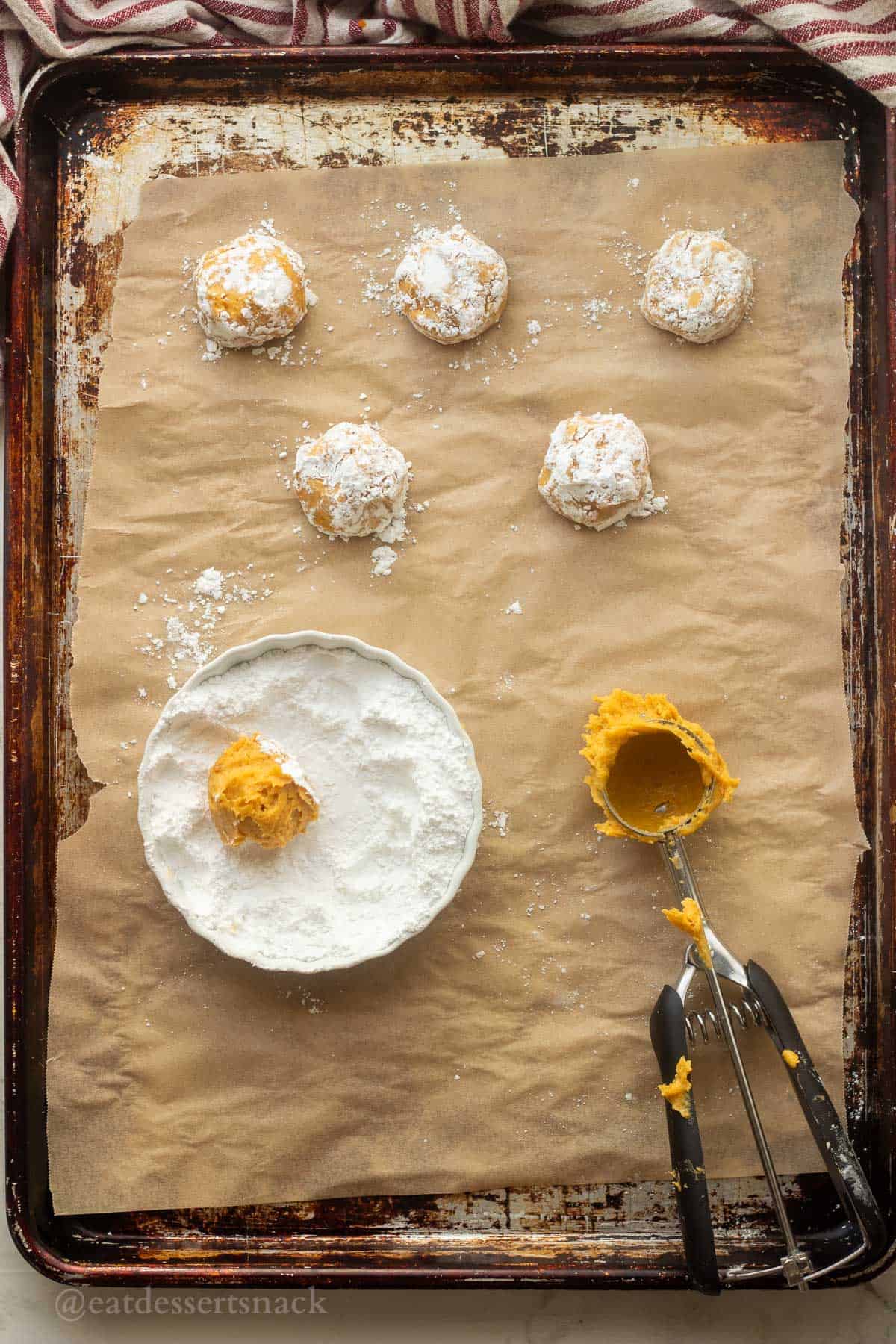 Powdered sugar on rolled raw pumpkin cookie dough balls.