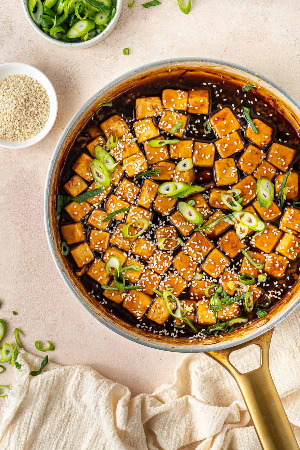 The finished teriyaki sauce in a frying pan with sliced green onions and sesame seeds.