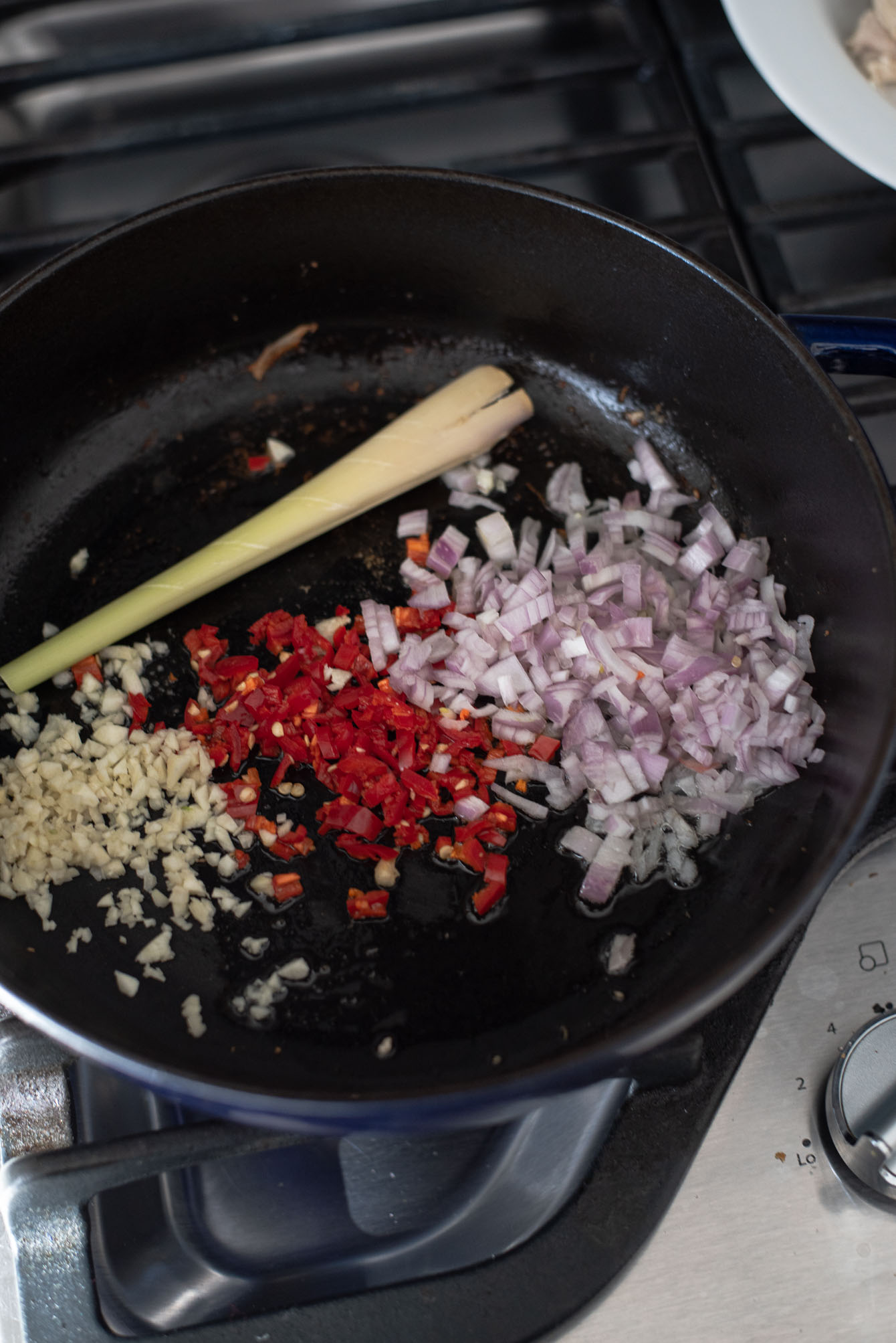 Garlic, shallot, red chili, lemongrass frying in a pot.