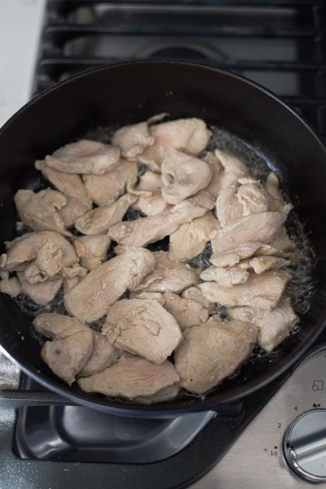 Chicken pieces are cooked in a pot.