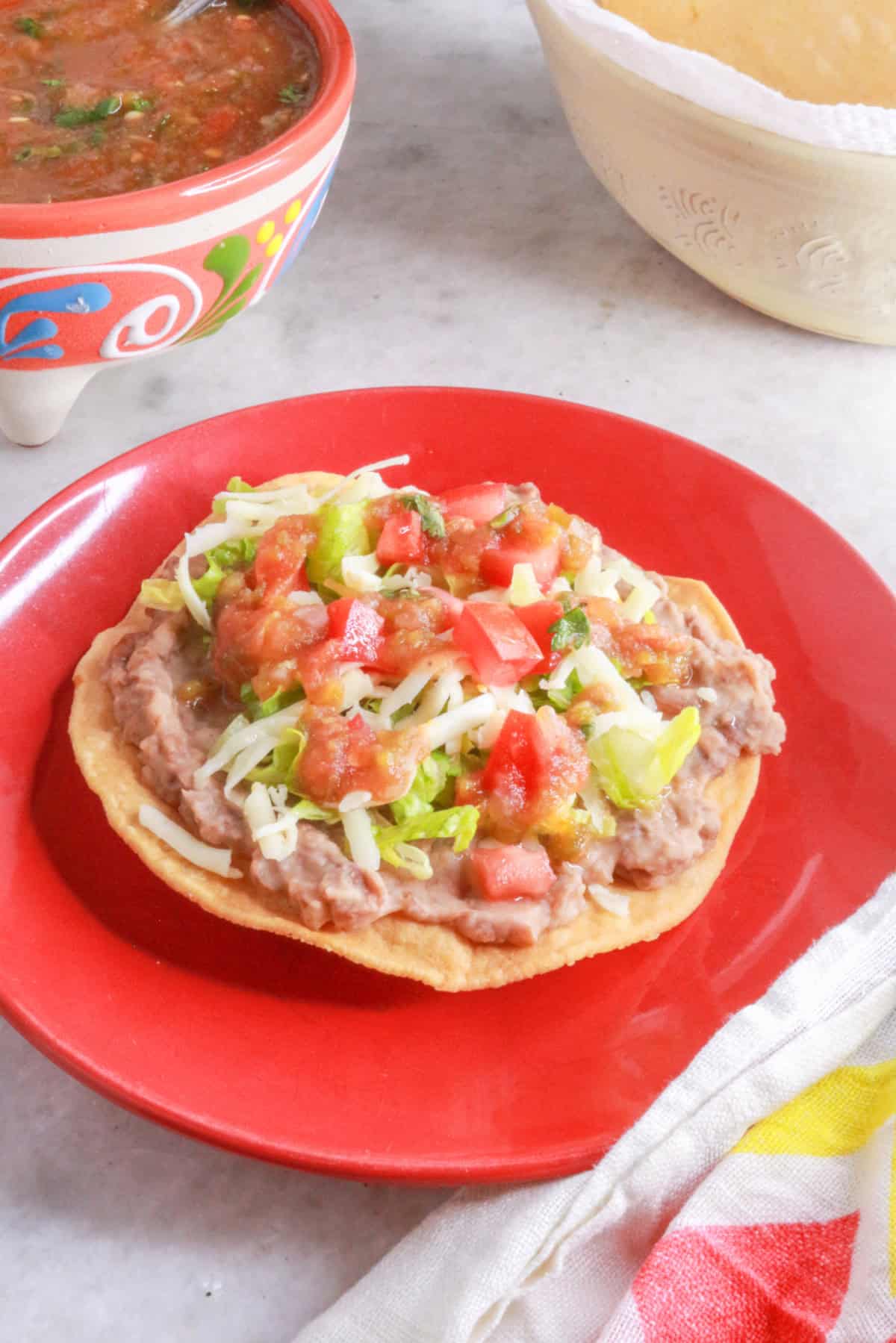 A red plate with a tostada de frijoles