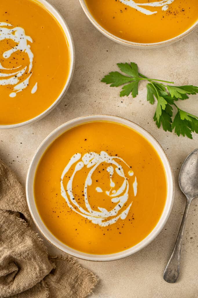 Serving the sweet potato soup into bowls with an extra drizzle of coconut milk.