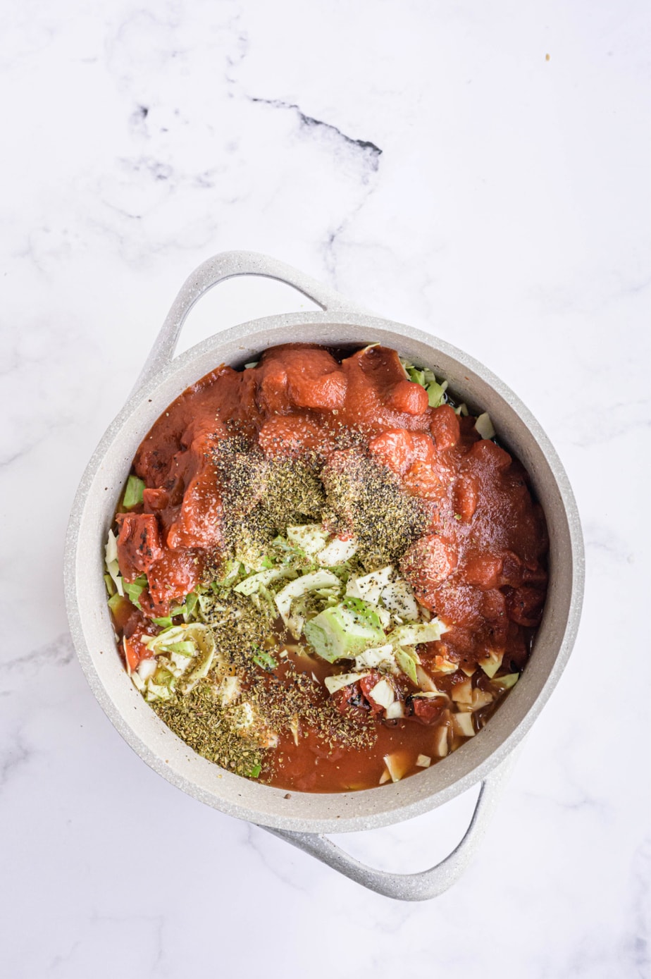 Raw ingredients for the soup are placed in a large white pot.