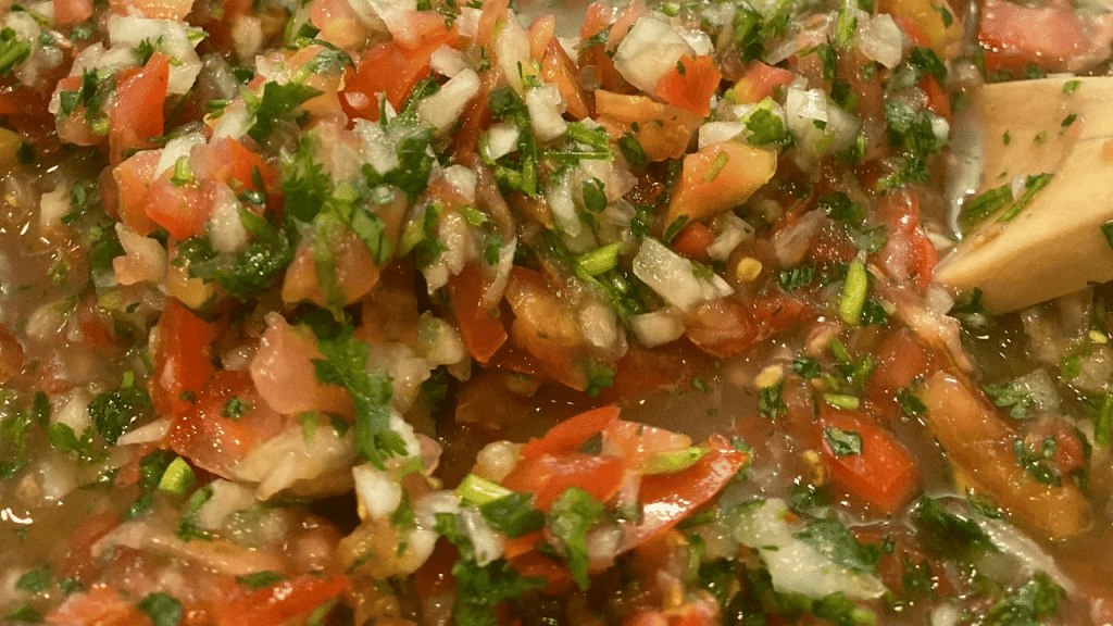 fresh salsa pico de gallo in bowl with spoon.