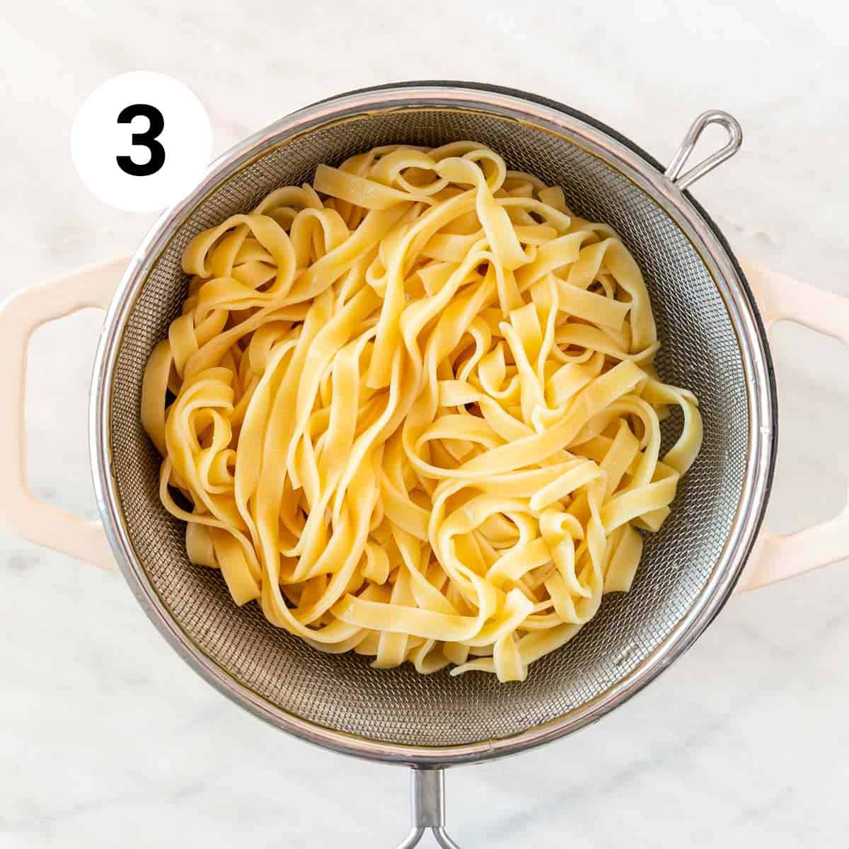 Pasta colander with fettucine in a pot.