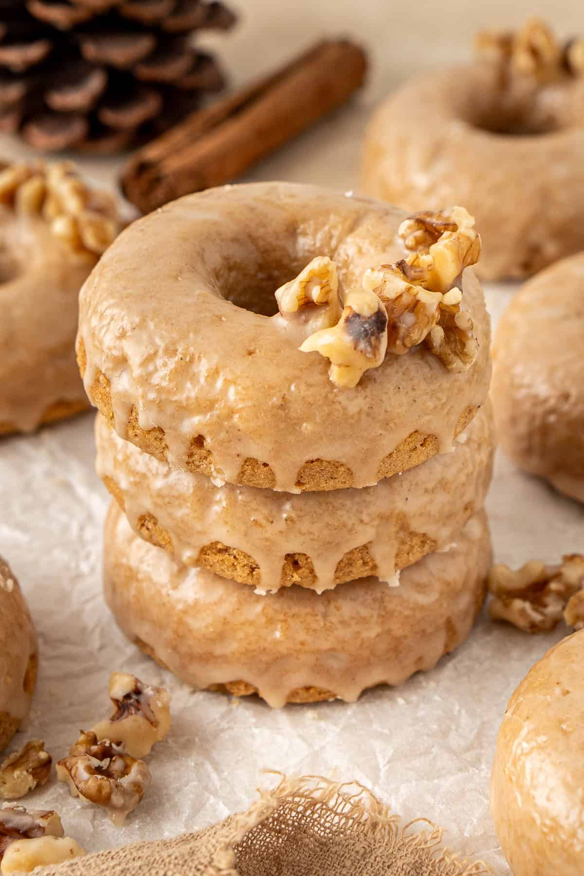 A stack of three maple glazed doughnuts with walnuts.