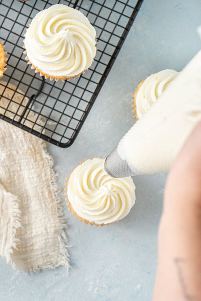 Piping the buttercream onto the cupcakes.