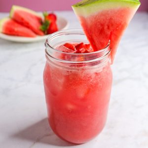 Watermelon Strawberry Agua Fresca in a glass garnished with a slice of watermelon
