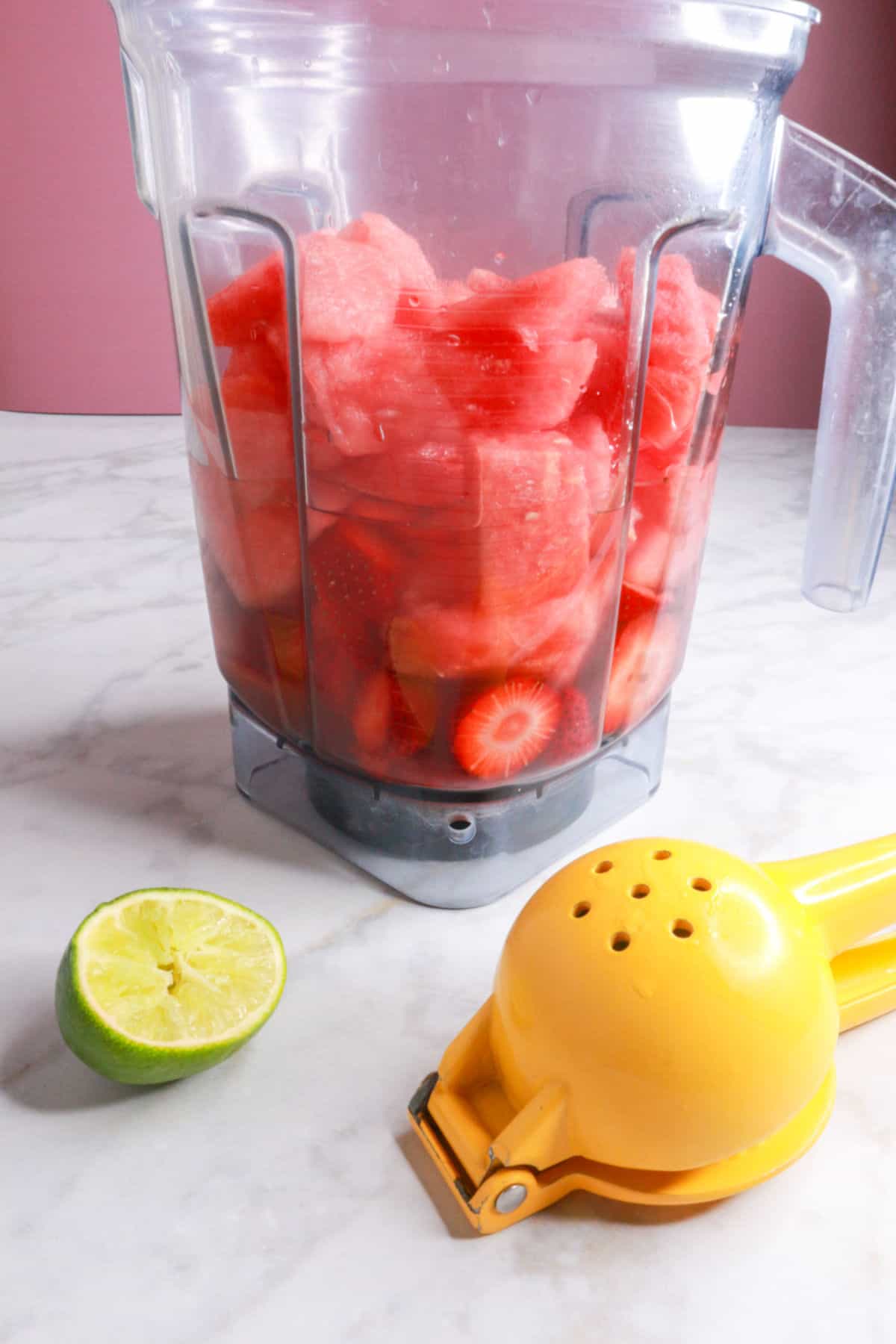 A blender with chopped watermelon and strawberries