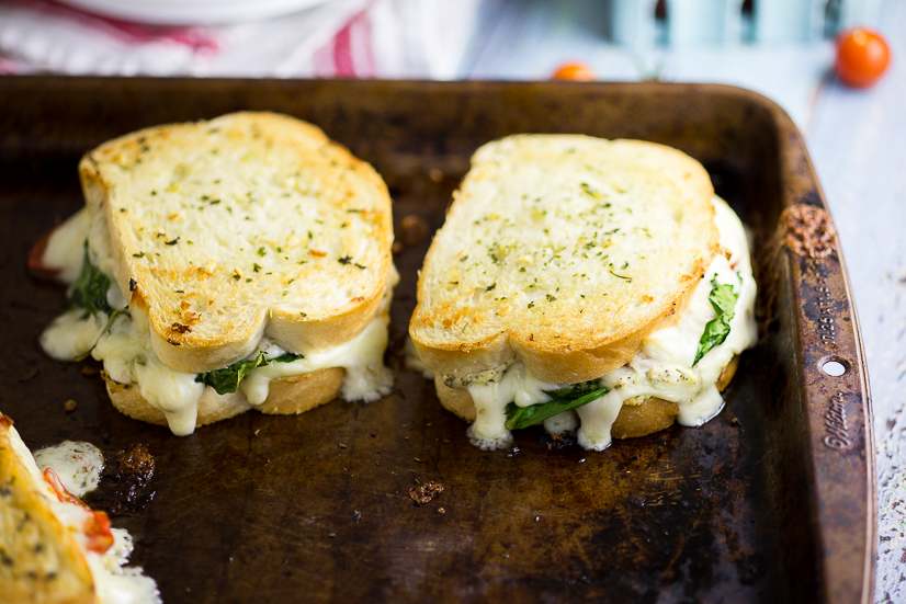 Oven Baked 5 Cheese White Pizza Grilled Cheese Recipe - Baked in the oven to golden, gooey perfection, this deluxe 5 Cheese White Pizza Grilled Cheese is the ultimate cheesy sandwich with 5 types of real cheese, a garlic herb ricotta spread, garlic butter, tangy cherry tomatoes and spinach. 