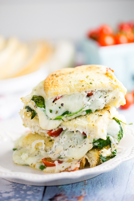 Oven Baked 5 Cheese White Pizza Grilled Cheese Recipe - Baked in the oven to golden, gooey perfection, this deluxe 5 Cheese White Pizza Grilled Cheese is the ultimate cheesy sandwich with 5 types of real cheese, a garlic herb ricotta spread, garlic butter, tangy cherry tomatoes and spinach. 