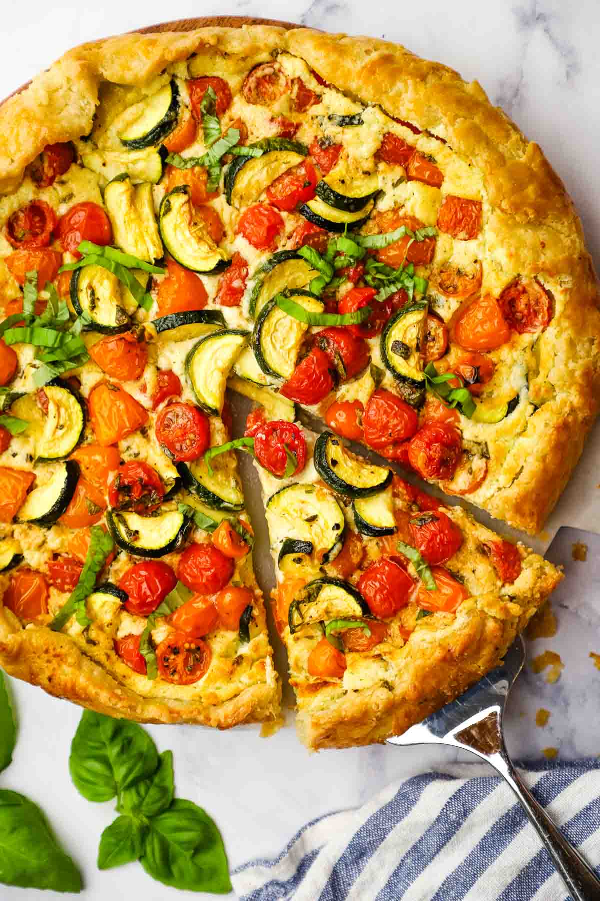 Overhead view of a zucchini tomato tart with one slice being removed.