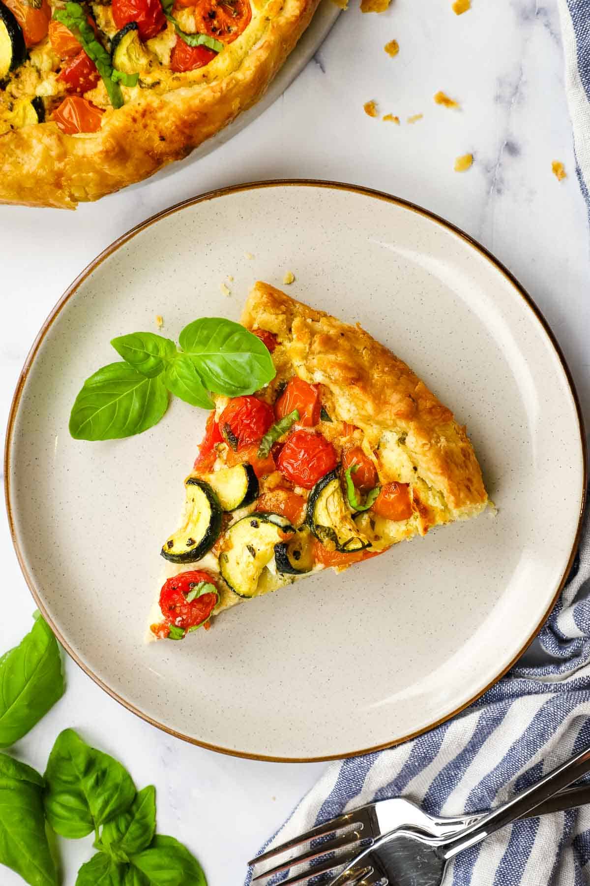 an overview of a slice of zucchini tomato tart on a plate