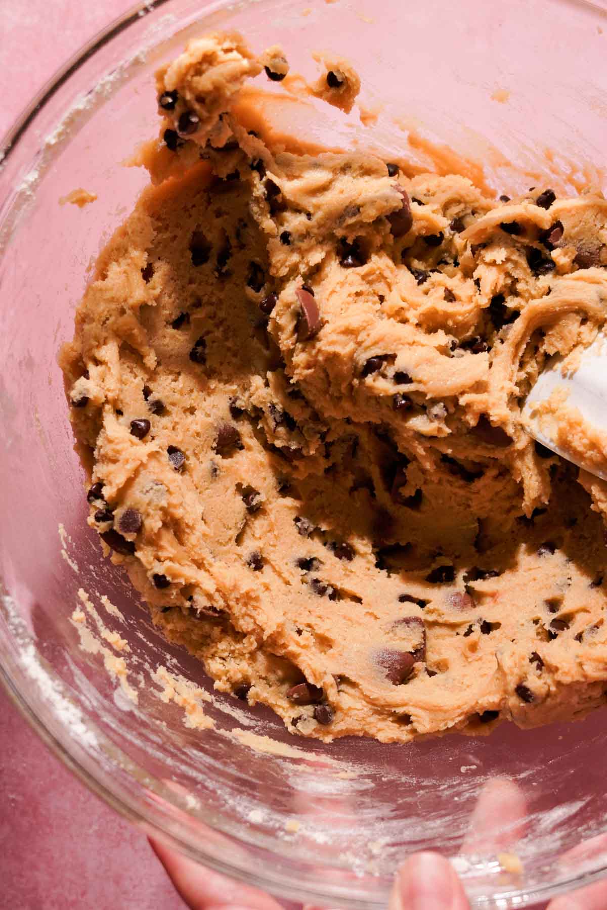 stirring cookie dough with chocolate chips using a silicone spatula