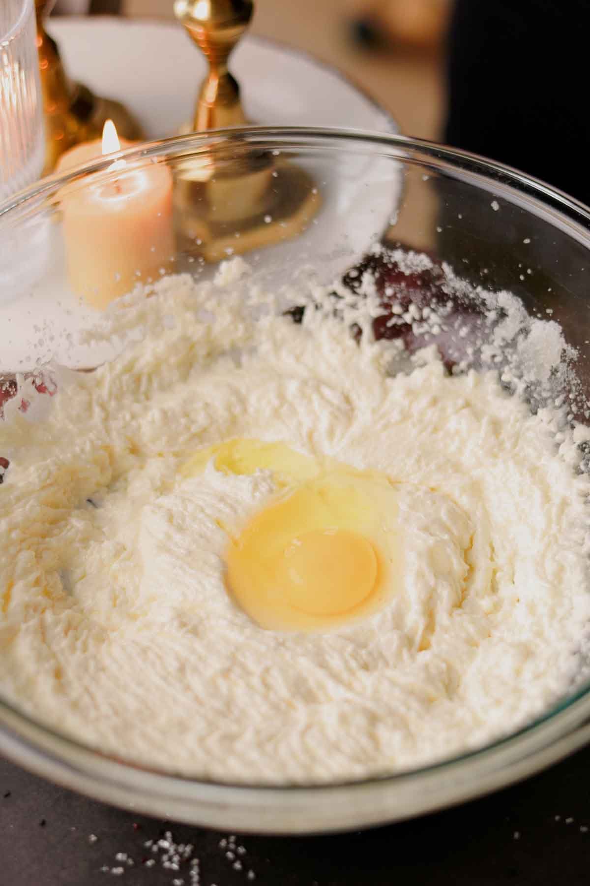 cracking an egg into the beaten butter, oil, and sugar