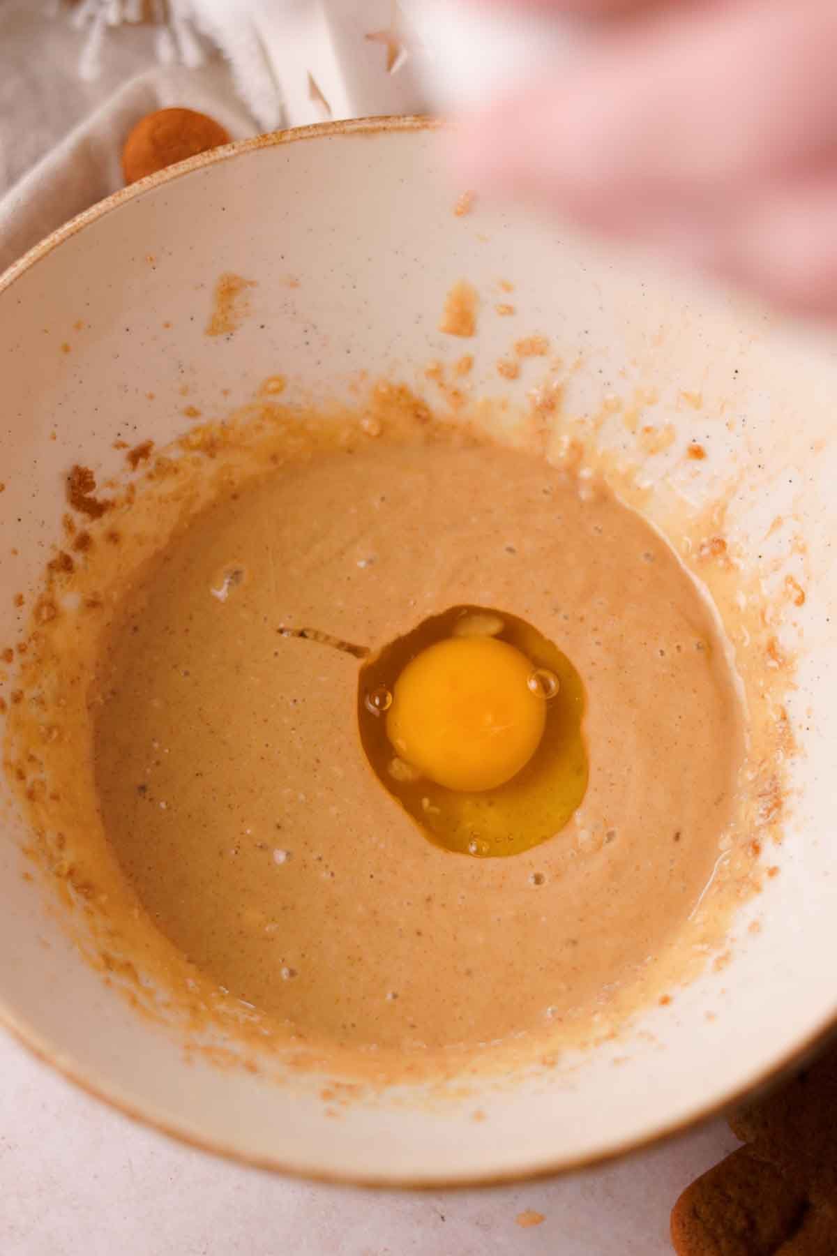 cracking an egg into the bowl of wet ingredients