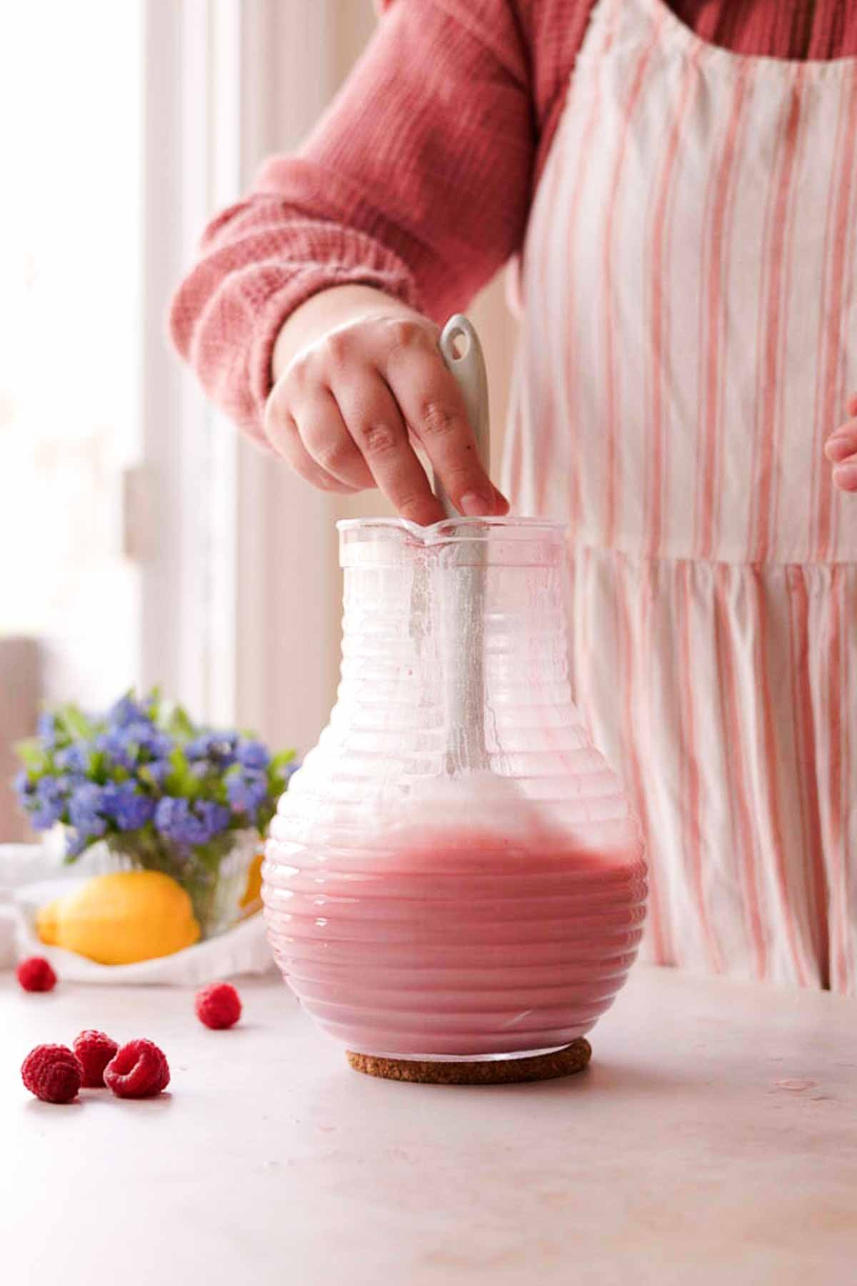 stirring raspberry posset mixture in pitcher