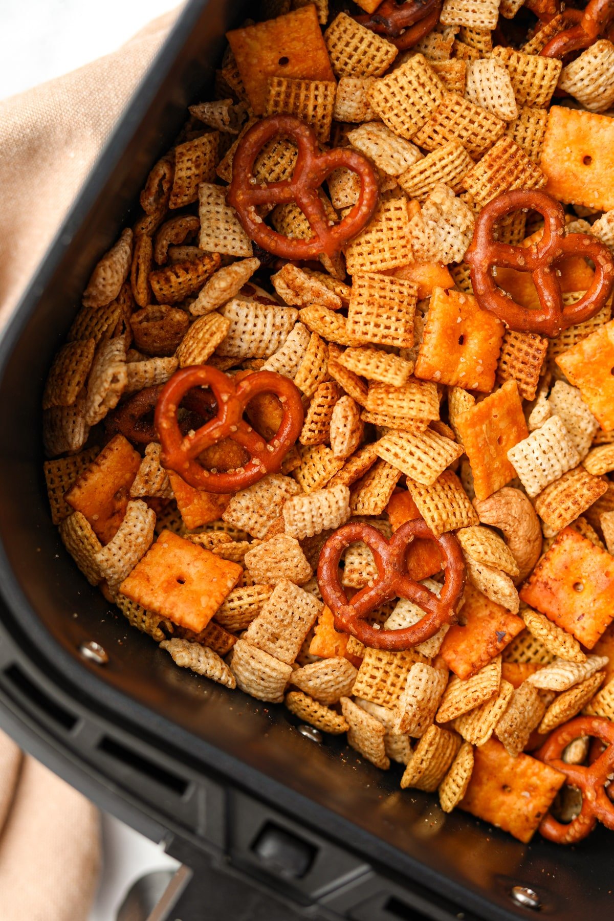 An air fryer basket filled with homemade Chex mix.
