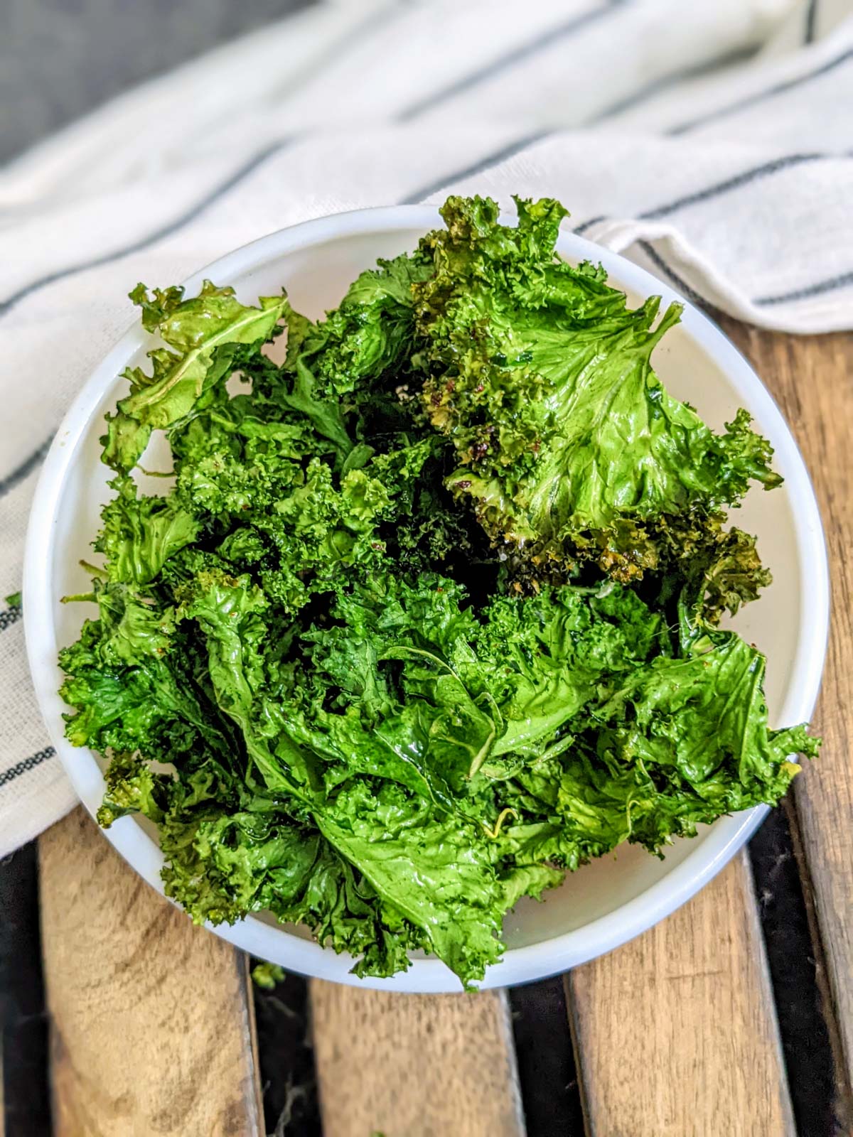 Kale chips after air frying in a white bowl.
