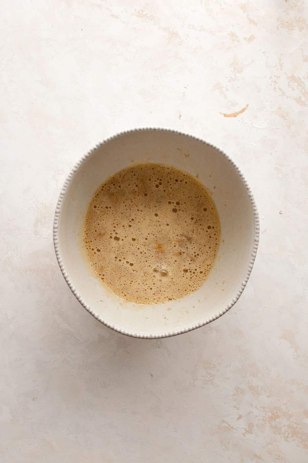 Mashed bananas, eggs, maple syrup, and vanilla extract whisked together in a mixing bowl until smooth.