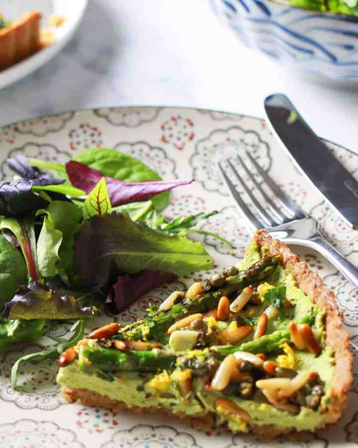 photo of a plate with a slice of vegan asparagus tart and some salad.