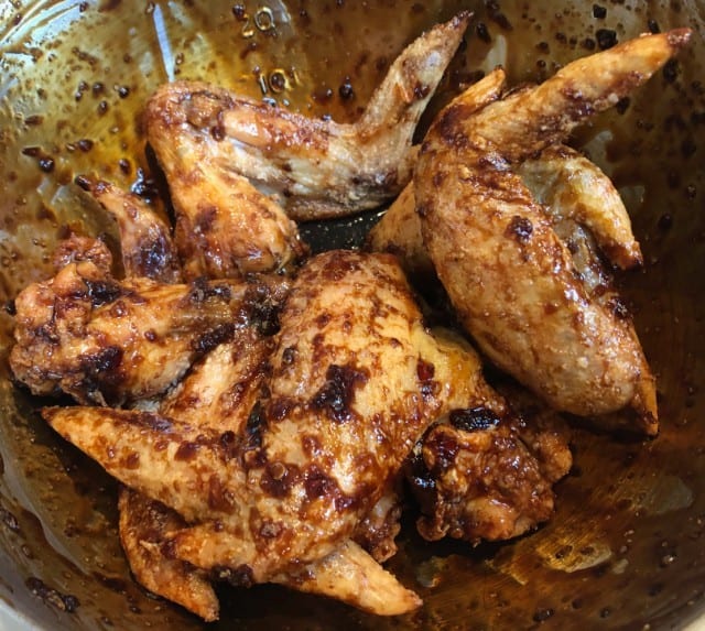 baked chicken wings in a bowl with sauce.