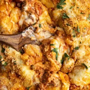 Overhead view of baked gnocchi with a spoon in the middle showing how gooey the casserole is.