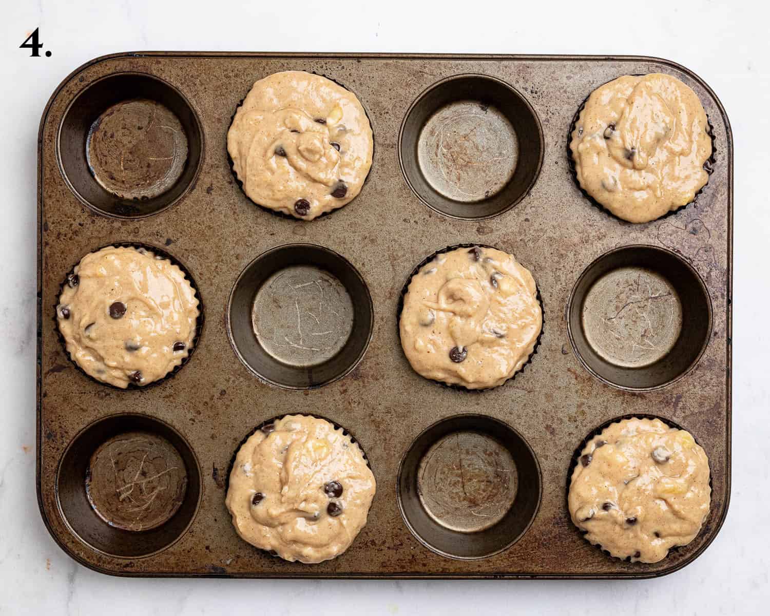 Step 4, the batter divided between the muffin cases.